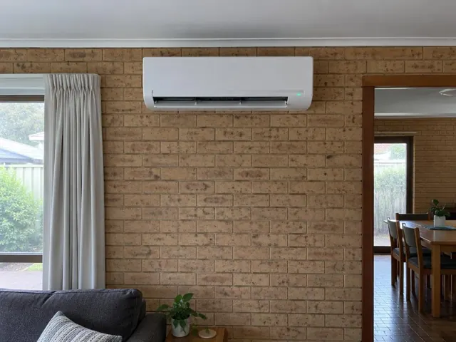 Wall-mounted split system running on a brick wall in a home living room in Paralowie