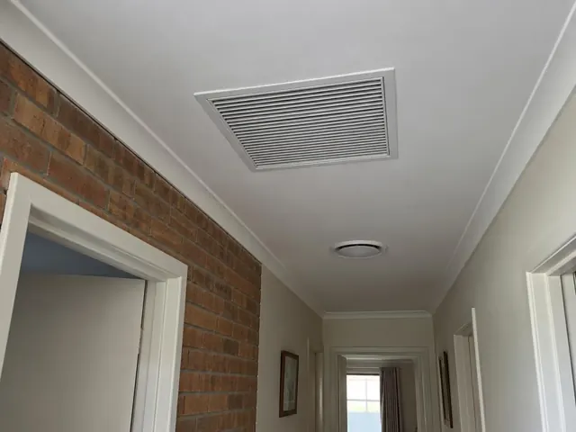 Ceiling return-air grille in a narrow hallway with brick feature wall and doorways in Mawson Lakes